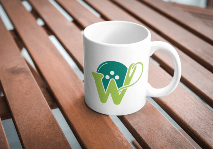 A white coffee cup on a wooden background featuring a "W" logo with a needle and a button